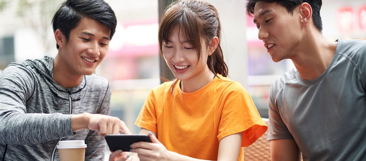 three young asian adults looking at cellphone